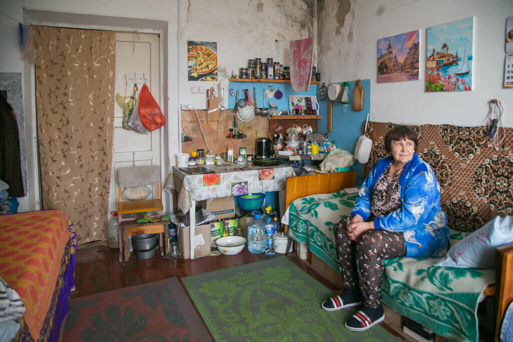 A woman is sitting on a sofa in her room in an accomodation center for idps in Ukraine that Mondo supported.